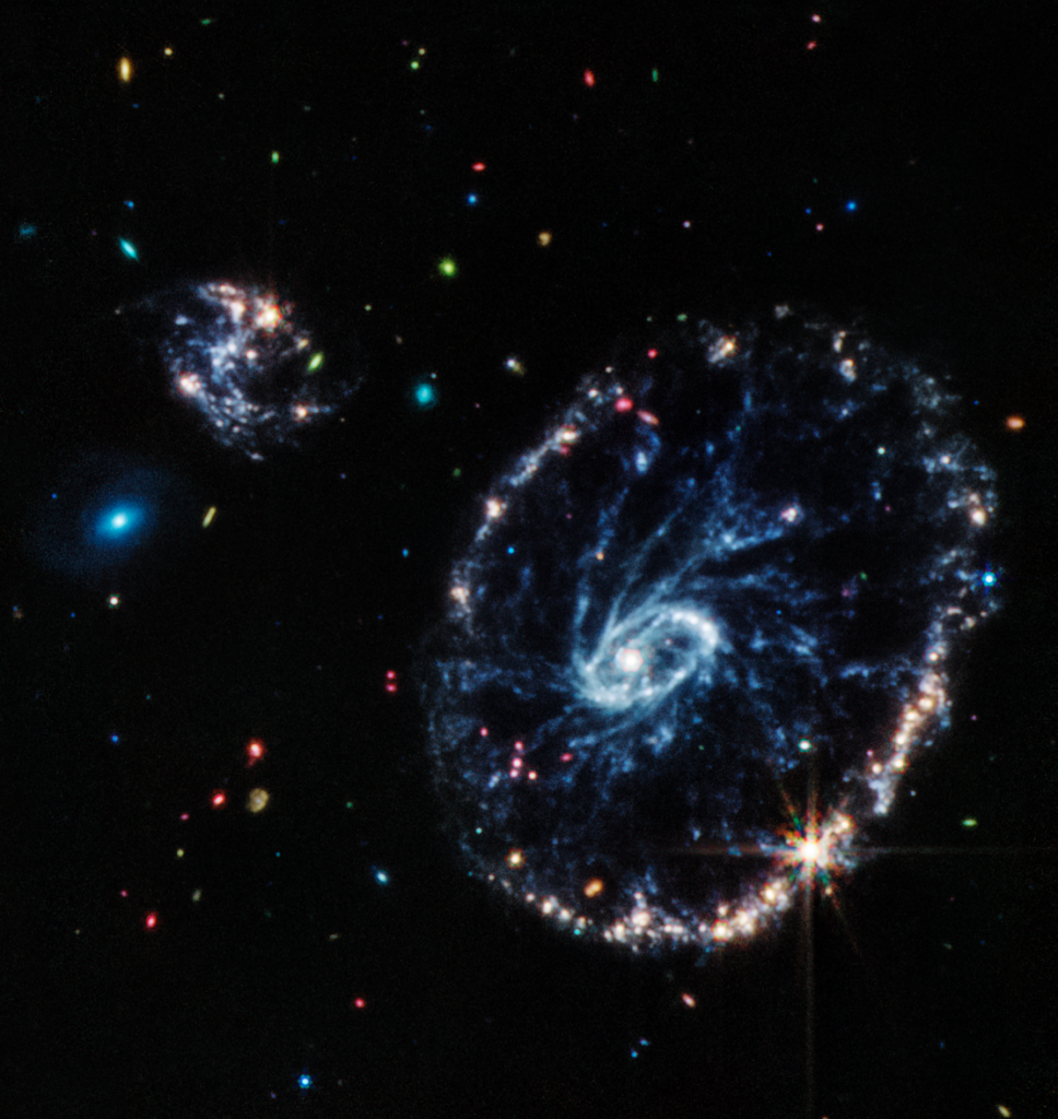 Esta imagen del instrumento de infrarrojo medio de Webb (MIRI) muestra la galaxia Cartwheel. Tiene datos de la cámara NirCam que revela estrellas jóvenes nunca antes vistas, mientras que la cámara MIRI revela regiones ricas en hidrocarburos y compuestos químicos, como polvo de silicato, muy similar al polvo de la Tierra. 